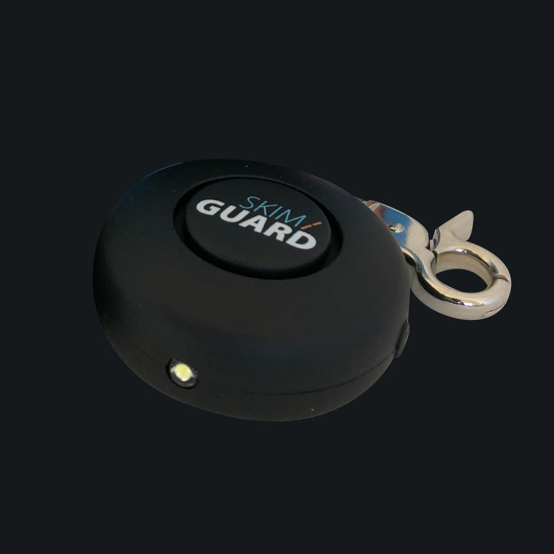 Angled view of the Skimguard Personal Alarm with front button and metal clip.