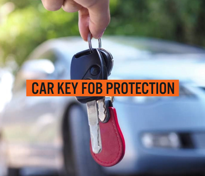Hand holding car keys with a red keychain in front of a blurred car, with 'CAR KEY FOB PROTECTION' text overlay.