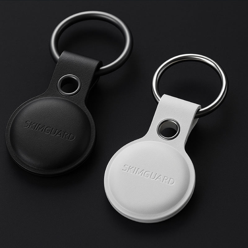 Black and white Skimguard leather Travel Traka pouches shown at an angled view on a dark background, featuring premium stitching, smooth leather texture, and stainless-steel key rings